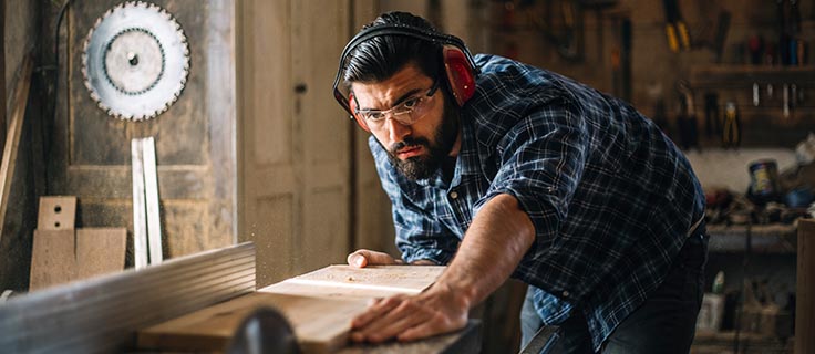 man doing woodwork with a saw.