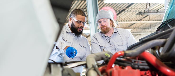 two mechanics inspect diesel truck engine.