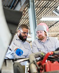 two mechanics inspect diesel truck engine.