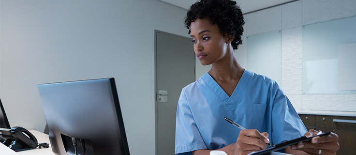 medical records technician reading computer screen and taking notes.
