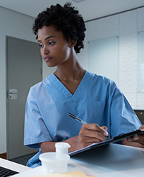 medical records technician reading computer screen and taking notes.