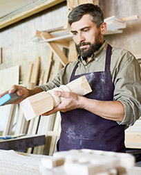 furniture maker sanding wood balusters.