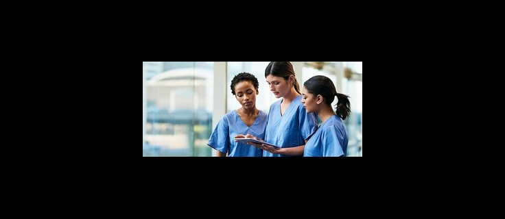 three healthcare students look at computer tablet.