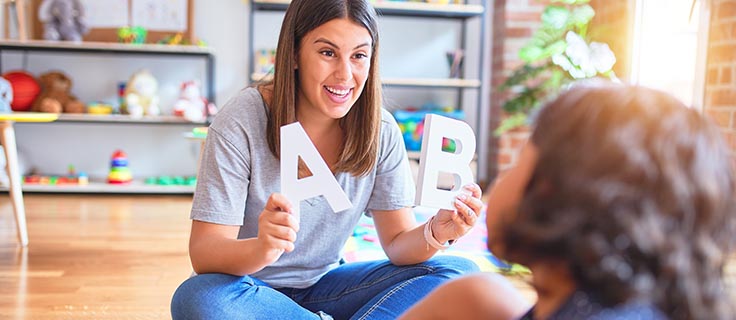 child care worker holding letters.