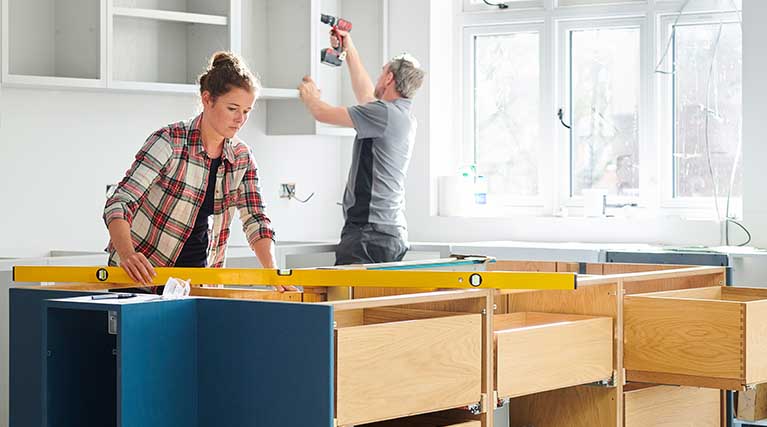 two people remodeling a home kitchen.