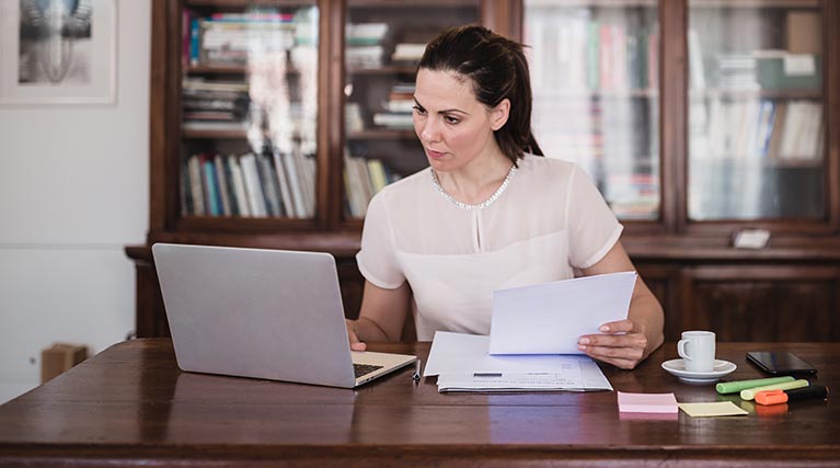 legal professional with paperwork using laptop in office.