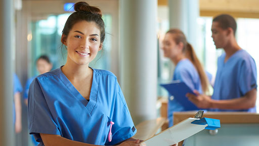female medical assistant holding a clipboard and smiling.