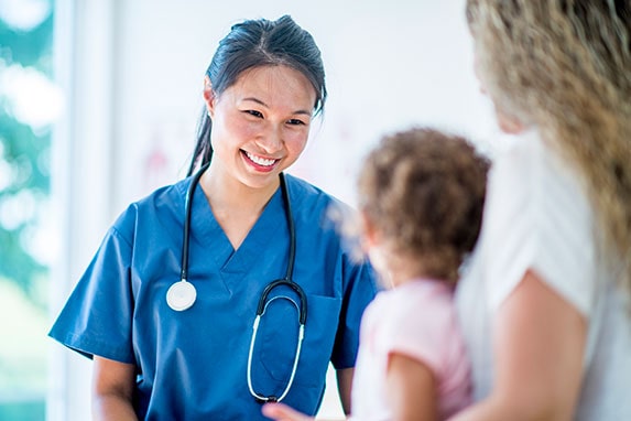 A medical assistant helping a mother a daughter.