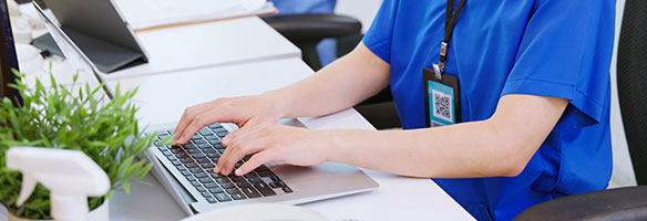 medical professional typing on laptop.