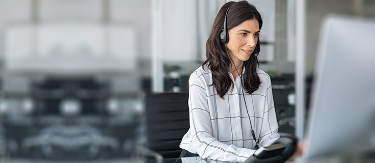 medical transcriptionist wearing headset working at desktop computer.
