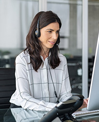 medical transcriptionist wearing headset working at desktop computer.