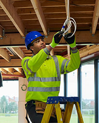 electrician on ladder working on electrical wiring.