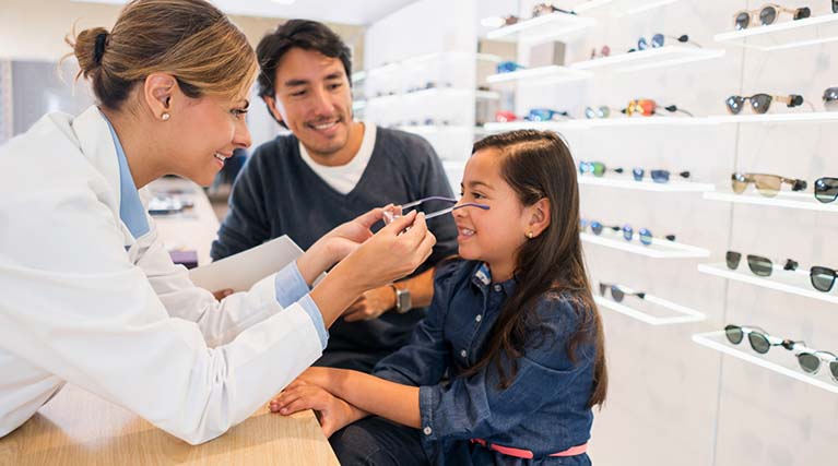 optician placing prescription glasses on child.