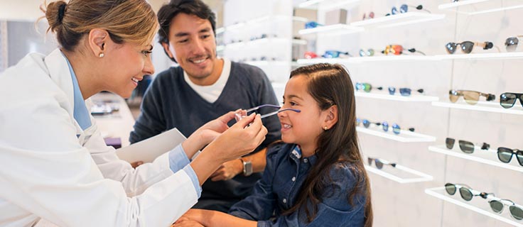 optician placing prescription glasses on child.