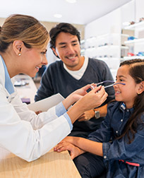 optician placing prescription glasses on child.