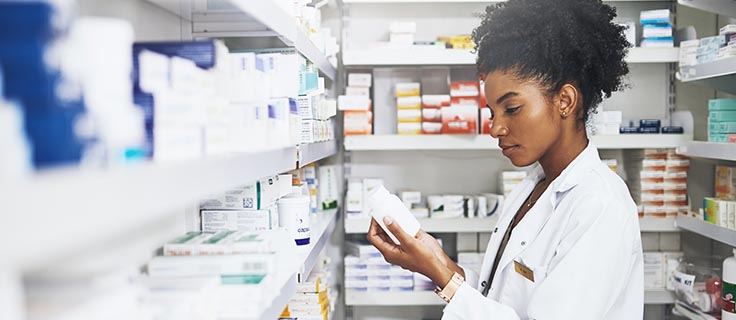 pharmacist reading prescription bottle in pharmacy.