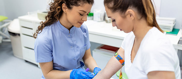 phlebotomist drawing blood from patient in exam room.