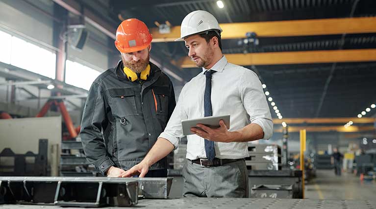 supervisor talking to employee in an industrial workspace.