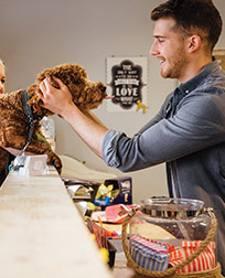 man petting a dog at front desk in a lobby.