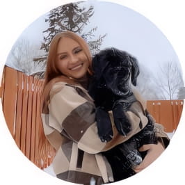 Penn Foster graduate, Jessica, holding large black dog for photo outdoors in winter.